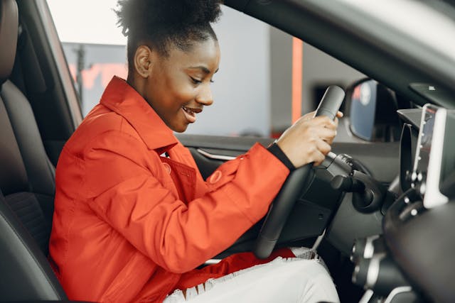 一名女子坐在车内，手扶方向盘的照片