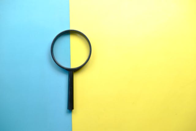左三分之一背景是蓝色，右三分之二背景是黄色。色块中间是一个放大镜