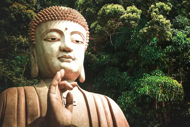 一座石像，背景是一片绿树